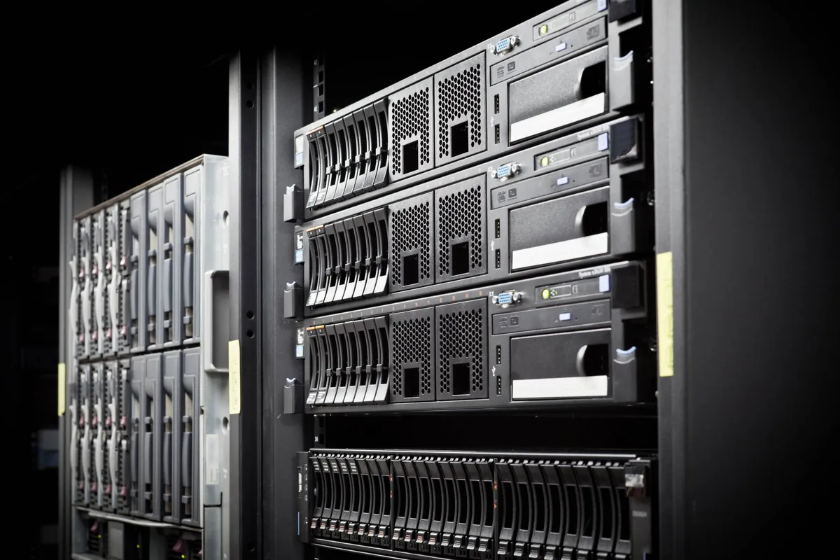 Server racks lining a dark aisle, with blue and amber status lights